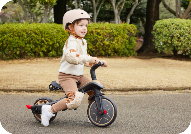 三輪車に乗る子どもと見守る家族